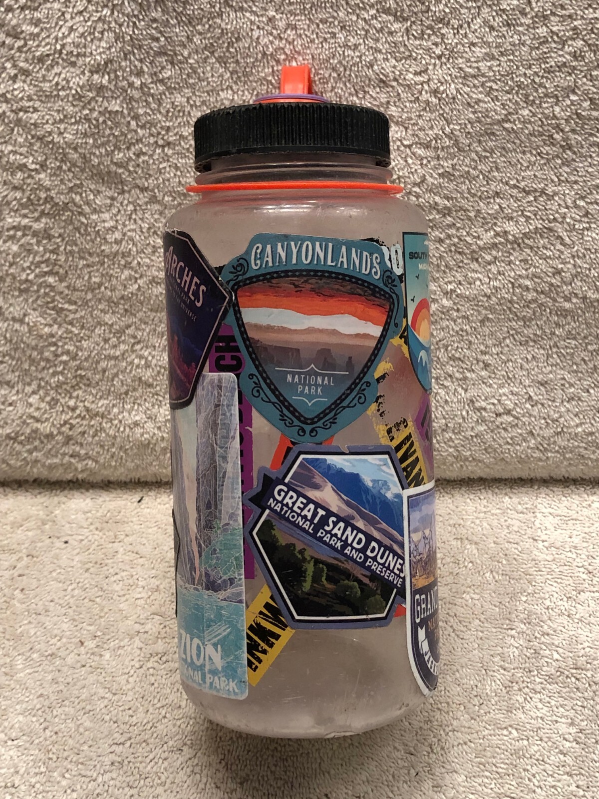 8 1/4 in tall empty bottle container by Nalgene with many National Parks Sticker